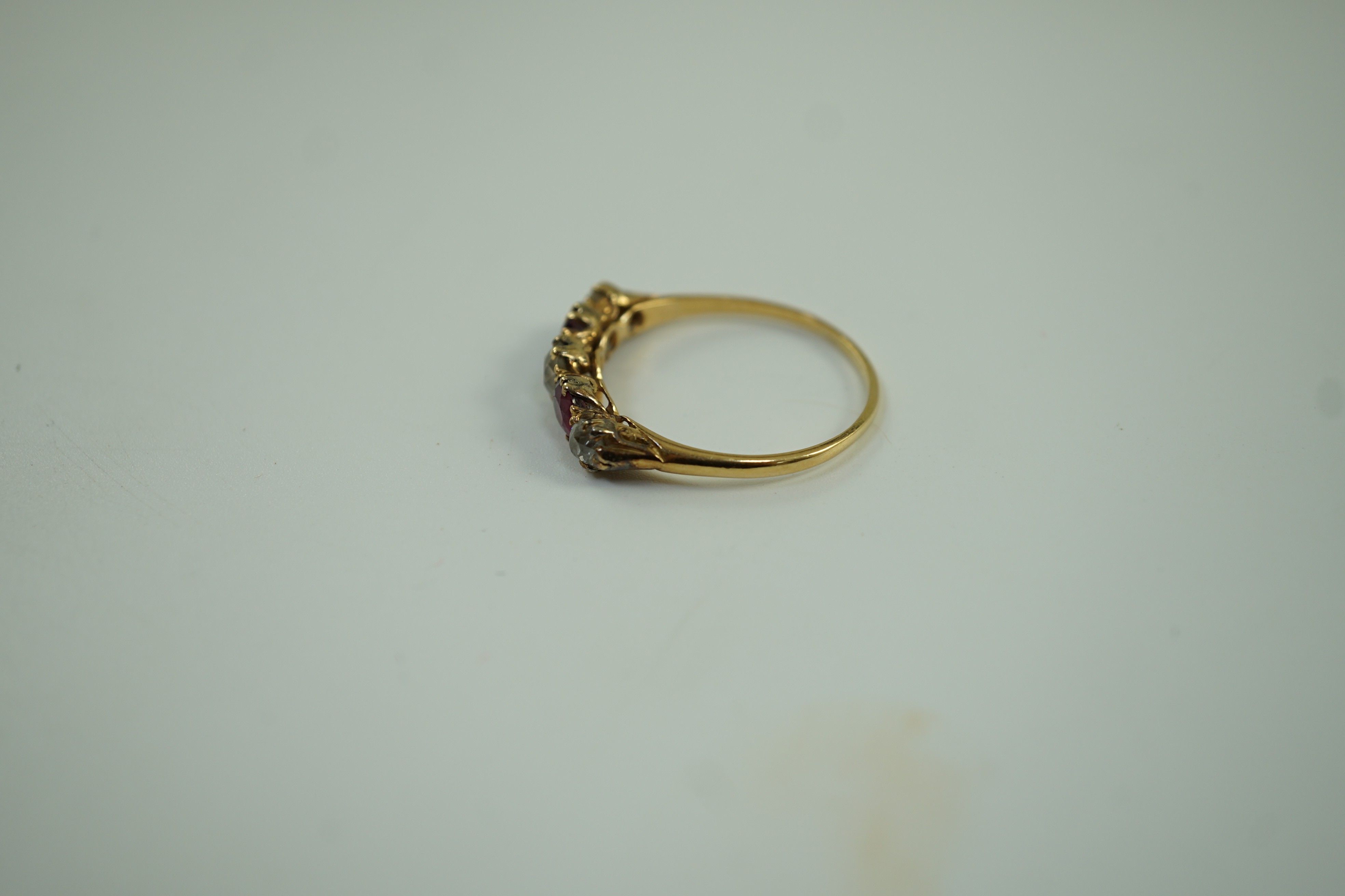 A yellow metal, three stone diamond and two stone ruby set half hoop ring, size V, gross weight 3.2 grams.